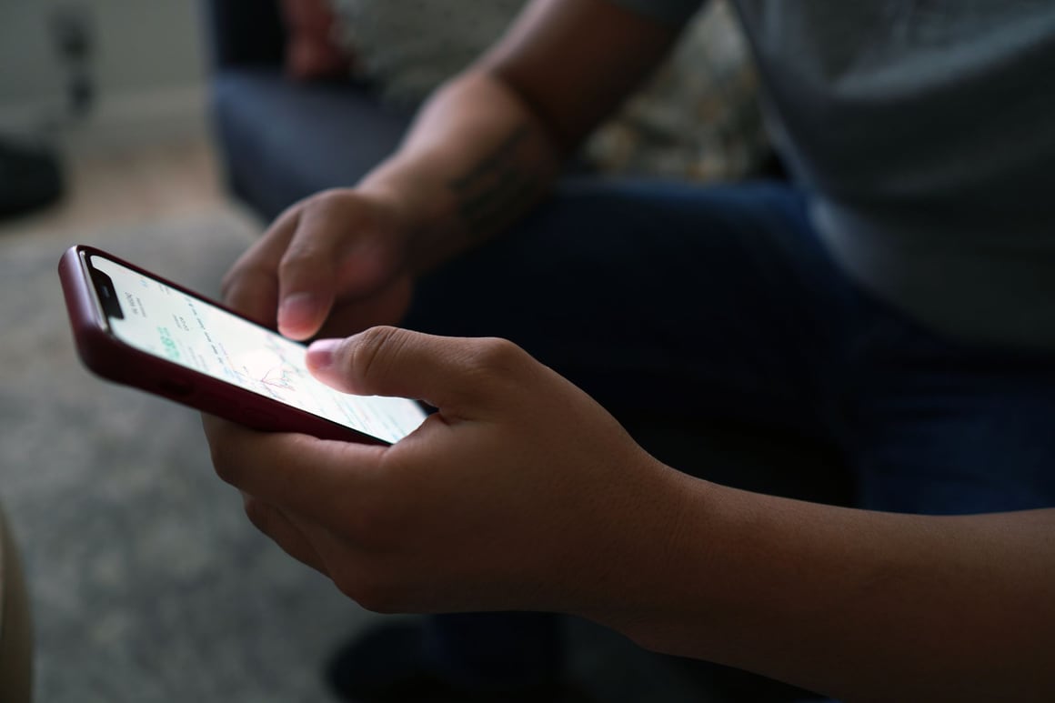 Hands using a phone while sitting indoors
