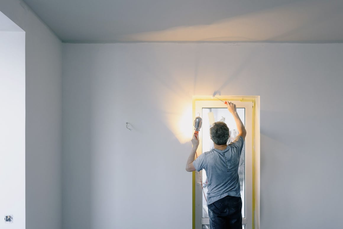 A pro fixing a door frame in a bright room