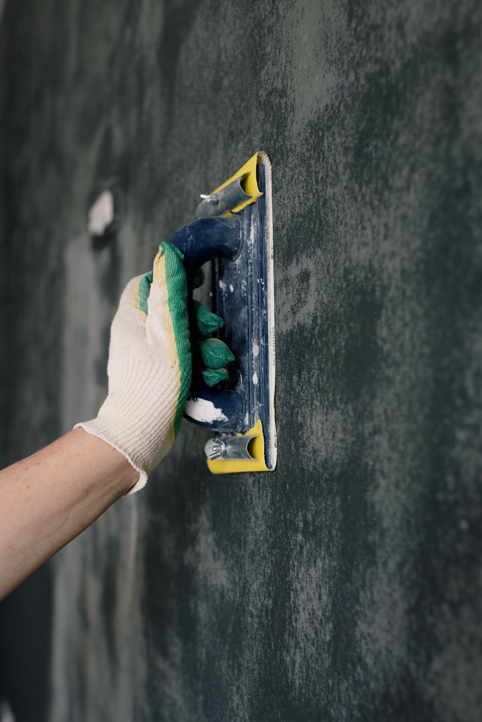 A gloved hand smoothing a patch on a wall
