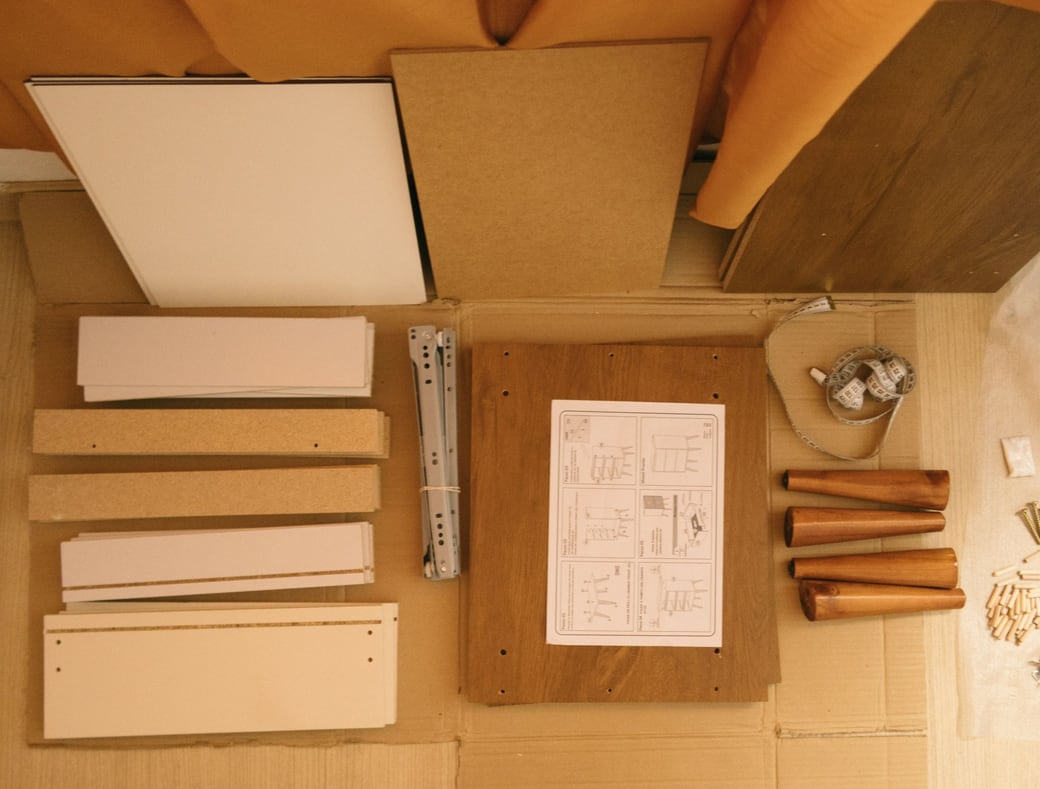 Furniture panels, drawer runners and hardware laid out beside instructions