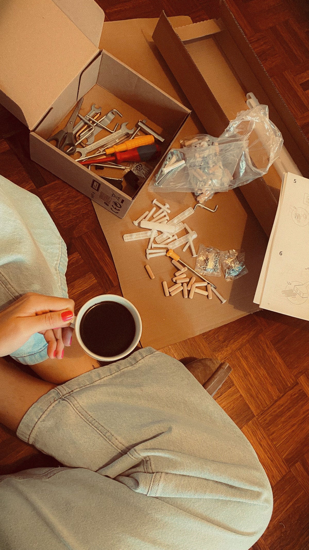 Furniture hardware, tools and open boxes on a wooden floor